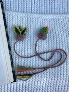 two crocheted plants sitting on top of a white blanket next to a book