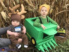 two children dressed up in costumes sitting next to each other on the ground with corn stalks behind them