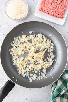 onions and meat are being cooked in a frying pan on the counter top next to other ingredients