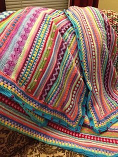 there is a multicolored crocheted blanket on the bed