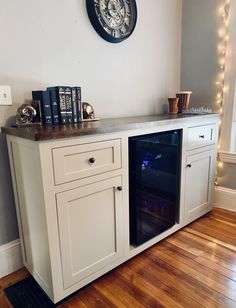 a white entertainment center with books on top and a clock mounted to the wall above it