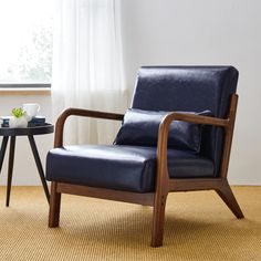 a blue leather chair sitting in front of a window next to a table with a cup on it