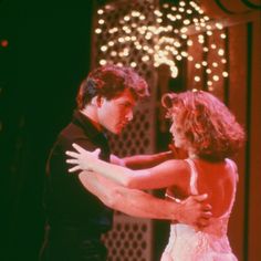 a man and woman dancing on stage with lights in the backround behind them