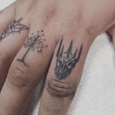 two fingers with tattoos on them, one has a dragon and the other has a tree