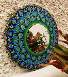 a blue and green mirror sitting on top of a stone wall next to a plant