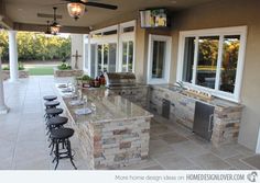 an outdoor kitchen with bar stools and grill