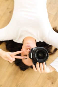 a woman holding a camera up to her face and making a peace sign with her fingers