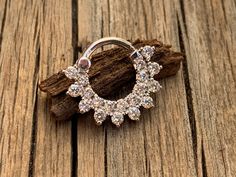 a close up of a pair of hoop earrings on a piece of wood next to some driftwood