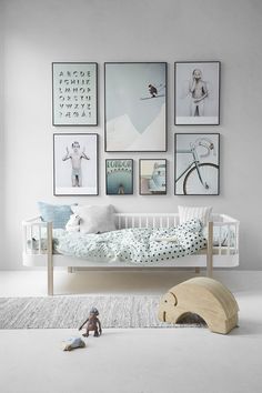 a child's bedroom with pictures on the wall and a crib in front of it