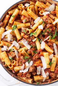 a skillet filled with pasta and meat covered in sauce, parmesan cheese and parsley