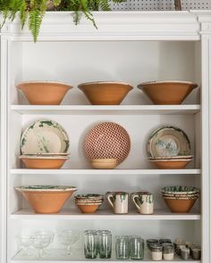 the shelves are filled with dishes and cups