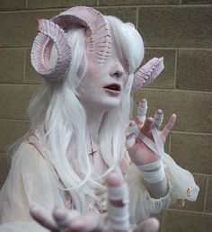 a woman with white hair and horns holding her hands up