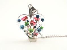 a heart shaped vase filled with flowers on a chain