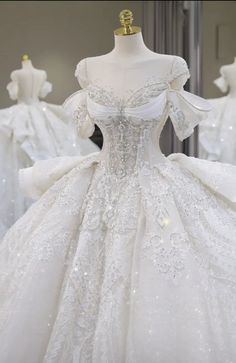 a white wedding dress on display in front of mannequins wearing gowns