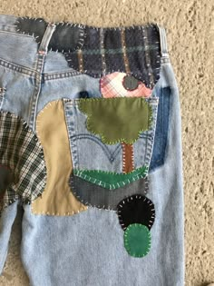 a pair of jeans with patches and trees on them