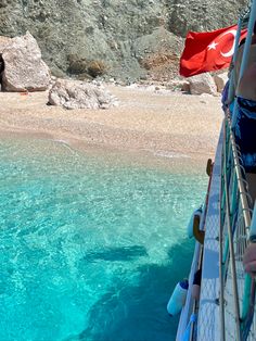 people are sitting on the deck of a boat looking out at the clear blue water