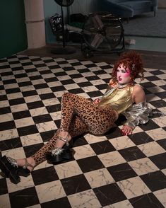 a woman with red hair is laying on the floor in leopard print pants and heels