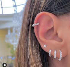 a close up of a person's ear with three piercings on top of it