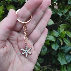 a person holding a gold and white snowflake key chain in their left hand