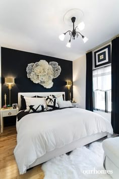 a bedroom with black walls and white bedding, chandelier, windows, and rugs