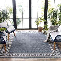 a living room with two chairs and a rug in front of a large glass window