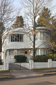 a large white house sitting on the side of a road next to a tree filled street