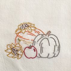 two pumpkins and an apple on a white towel