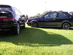 two cars parked in the grass next to each other