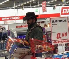 a man in a hat is reading a magazine at a store with other items for sale