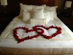 two hearts made out of flowers on a bed with the words rose petals on the bed