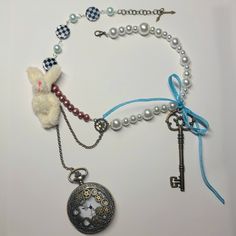 This necklace is inspired by the White Rabbit from Alice in Wonderland. It features a real, working pocket watch hanging from a bronze chain. The pocket watch hangs low enough that you are able to check the time while wearing it. There is also a fluffy, plush rabbit charm, a big, bronze key, a couple of gear and clock charms, a blue bow, and a mix of real pearl beads, faux pearl beads, and glass beads. If tugged, the bow can be undone so where and store with care. But if it does come undone, it can easily be retied. This necklace is about 17 1/2 inches long at its shortest and has an extension chain that is almost 2 inches long. If you need it lengthened more, please message me or leave a note on your purchase telling me how long you'd like it to be. This necklace does feature delicate, br Alice In Wonderland Necklace, Rabbit From Alice In Wonderland, Rabbit Necklace, Plush Rabbit, Rabbit Charm, The White Rabbit, Come Undone, Real Pearls, Blue Bow