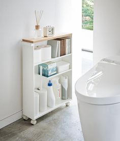 a white shelf with bottles and other items on it next to a toilet in a bathroom