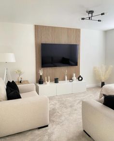 a living room filled with furniture and a flat screen tv mounted on the wall above it