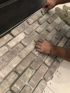 a man laying tile on top of a floor