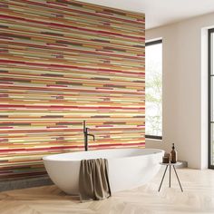 a bath tub sitting in front of a window next to a wall with multicolored stripes on it