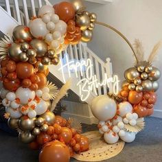 an orange and white balloon arch with happy birthday written on it