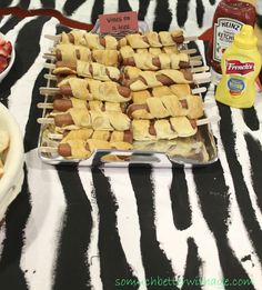 a table topped with lots of food and condiments on top of zebra print cloth