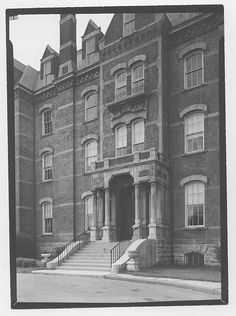 an old black and white photo of a building with stairs leading up to the front door