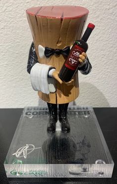 a figurine holding a bottle of wine on top of a table