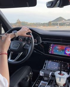 a woman is driving an audi car on the road with her hands on the steering wheel