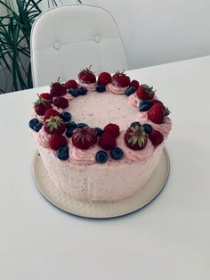 a cake with berries and blueberries on it sitting on top of a white table