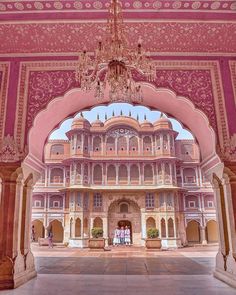 an ornate building with chandelier hanging from it's ceiling and pink walls