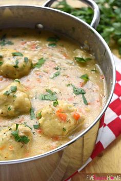 a pot filled with soup and dumplings on top of a red checkered napkin