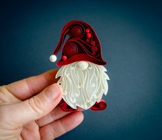 a hand holding an ornament in the shape of a gnome's hat