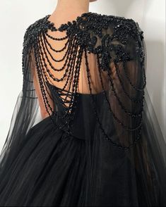 the back of a woman's black dress with beads on it