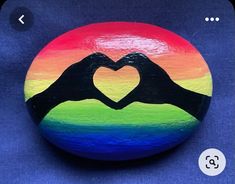 a painted rock with two hands making a heart