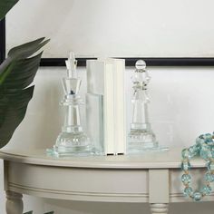 two glass candlesticks sitting on top of a white table next to a book