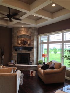 a living room with two couches and a fireplace in the center, surrounded by large windows