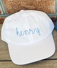 a white hat with the word henry embroidered on it sitting next to a blue bottle