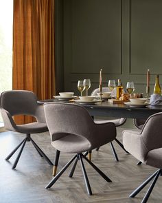 a dining table with four chairs around it and wine glasses on the table in front of it